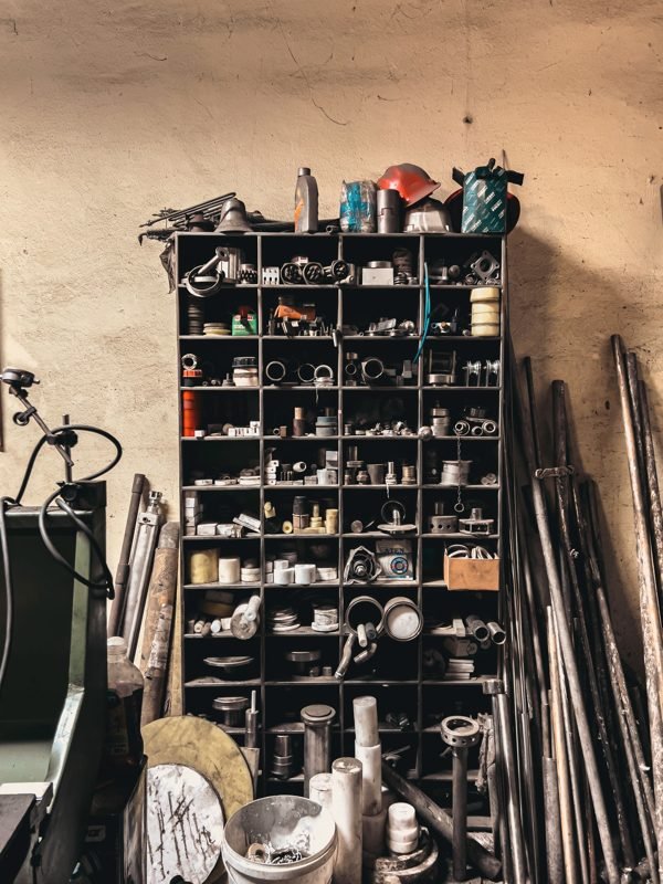 A tall cubby rack holding fittings and small parts against a wall