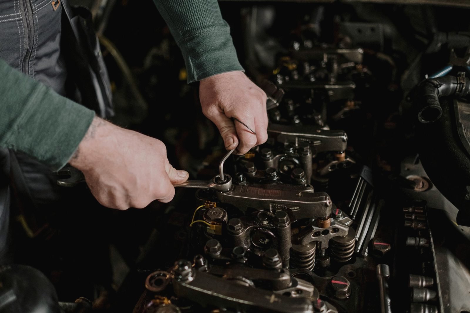 Hands using a wrench on an exposed engine valve train