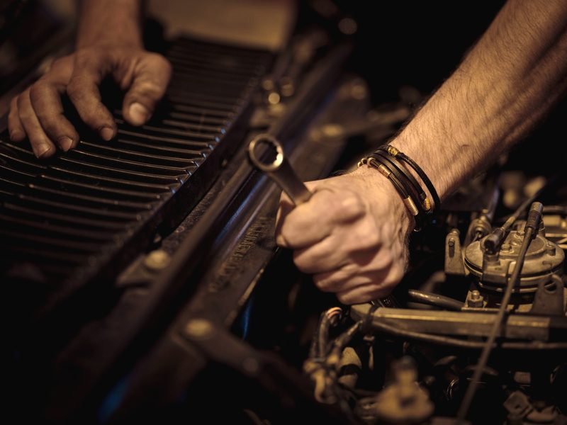 A hand gripping an open-end wrench over an engine
